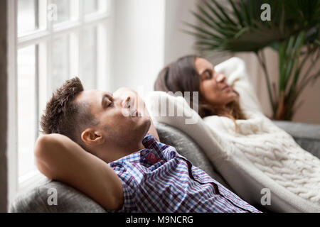 Young couple resting on comfortable couch together at home, happy man and woman enjoying relaxation or nap dozing on sofa with eyes closed, calm famil Stock Photo
