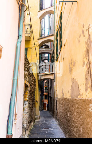 Narrow dark alley in an Italian medieval traditional town with weathered walls and buttresses between buildings Stock Photo