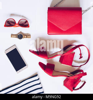fashion blog concept on white background. flat lay of a minimal set of female accessories:goldenwatch, red sandals , purse, mobile phone Stock Photo
