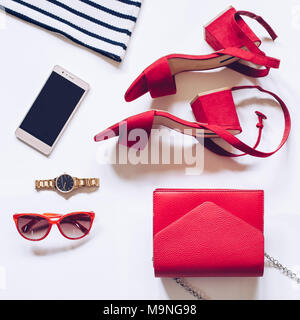 fashion blog concept on white background. flat lay of a minimal set of female accessories:goldenwatch, red sandals , purse, mobile phone Stock Photo