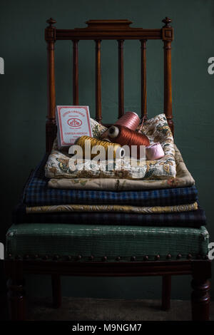 Collection of fabrics and vintage French spools on antique chair Stock Photo