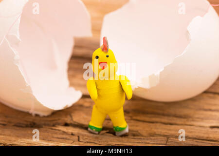 A yellow easter chicken with white egg shells on a wooden background Stock Photo