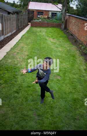 Pakistani boy playing with a ball in back-garden, Rugby, England Stock Photo