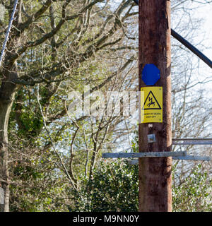 High voltage power line wooden post with a danger of death warning sign Stock Photo