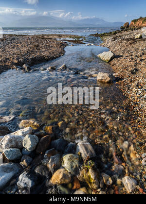 A stream flowing into the Menai Stait at Lleiniog Beach, Anglesey, North Wales UK Stock Photo