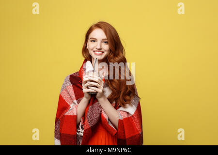 Lifestyle Concept: Portrait of woman basking with plaid and enjoy drinking chocolate Isolated over vivid yellow background Stock Photo