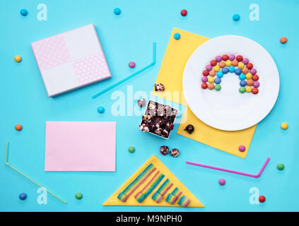 Colorful still life with sweets and present on blue background. Stock Photo
