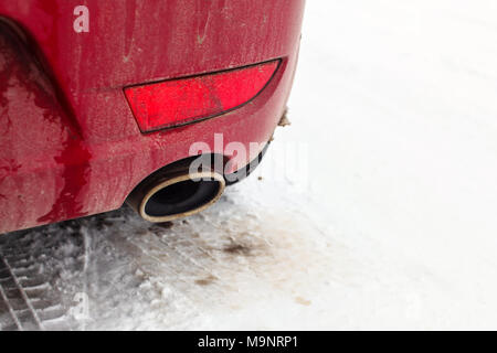 Detail on exhaust pipe of a red car parked on snow covered road. Stock Photo