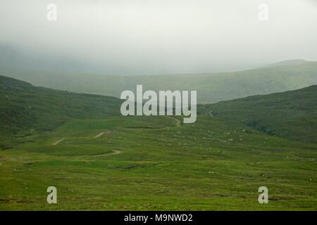 A winding road disappears into the mist in the Highlands of Scotland. Stock Photo
