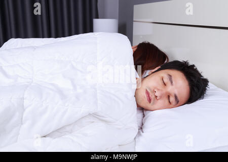 sick young man sleeping on bed with his wife Stock Photo