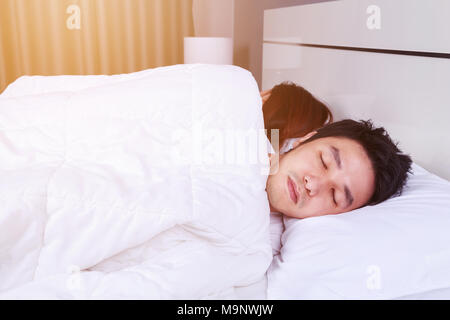 sick young man sleeping on bed with his wife Stock Photo
