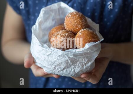mini donuts in a paper bag in the hands of a girl Stock Photo