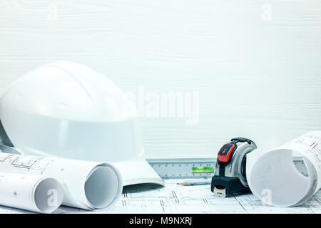 protective helmet, blueprint rolls, tape measure, bubble level on contractor workplace table Stock Photo