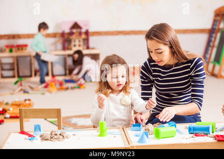 the teacher is teaching the girl to Make sand shapes Stock Photo