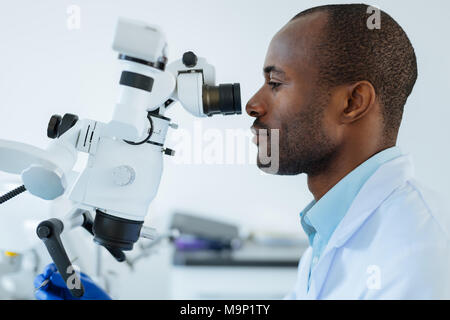 Side view of male dentist using microscope Stock Photo