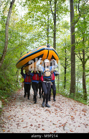 Group of rafters carrying inflatable boat over their heads to river Soca near Bovec, Triglav, Slovenia Stock Photo