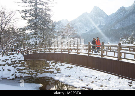 A man and woman are walking over a wooden bridge in Seoraksan National Park, Gangwon-do, South Korea.  Seoraksan is a beautiful and iconic National Park in the mountains near Sokcho in the Gangwon-do region of South Korea. The name refers to Snowy Crags Mountains. Set against the landscape are two Buddhist temples: Sinheung-sa and Beakdam-sa. This region is hosting the winter Olympics in February 2018. Stock Photo