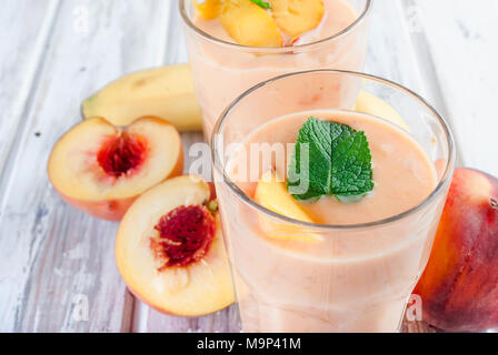 refreshing Summer smoothie or milkshake with apricot, peach and banana, mint, yogurt in glass with ingredients, on white wooden table, copy space, Stock Photo