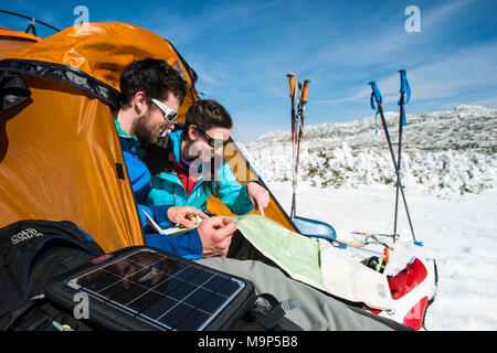 Man and woman setting up campsite in winter in mountains during daytime, New Hampshire, USA Stock Photo