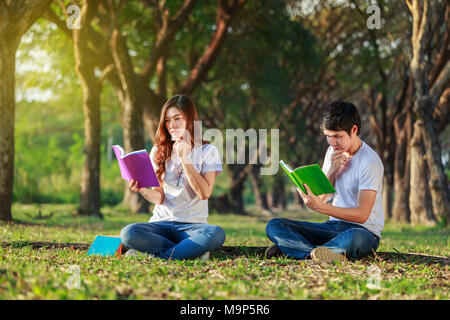 man and woman sitting and reading a book in the park Stock Photo