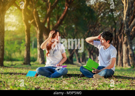 man and woman sitting and reading a book in the park Stock Photo