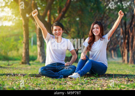 happy young couple with arm raised in the park Stock Photo