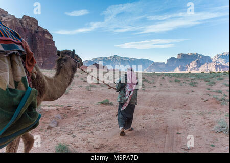 Bedouin walking with camel in Wadi Rum, The Valley of the Moon, is a valley cut into the sandstone and granite rock in southern Jordan. Stock Photo