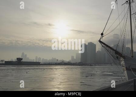 Chicago winter skyline over water with city and horizon over water and silhouette of ship mast in foreground Stock Photo