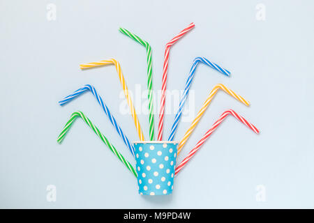 Flat lay of paper cup polka design with colorful drinking straws on pastel blue background minimal creative concept. Stock Photo