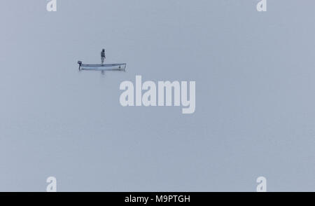 North Wales, UK 28th March 2018, UK Weather:  A further spell of snowfall and colder temperatures hits North Wales with further snow expected in the coming week. A lone fly fisherman on a boat braving the cold conditions and wintry showers on Llyn Brenig, Conwy County, North Wales © DGDImages/Alamy Live News Stock Photo