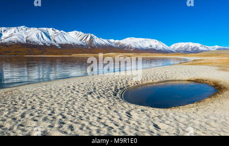 Sandy beach with pool, Khoton Lake, snow-covered mountains in the back, Mongolia Stock Photo