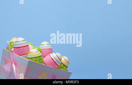Colored Easter eggs in paper basket pastel colors on blue background. Easter theme. Stock Photo