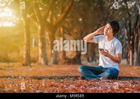 young man listening to music with headphones from mobile in the park Stock Photo