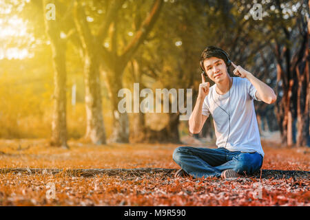 young man listening to music with headphones from mobile in the park Stock Photo