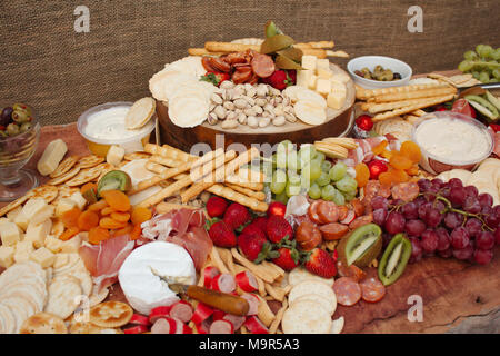 A bright & colorful selection of fruit, nuts, cheeses, dips, Deli meats and crackers spread across a beautiful slab of wood. Stock Photo