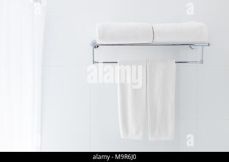 White bathroom towels hanging on the rack in a white bathroom near shower, good for clean and fresh theme or refresh concept Stock Photo
