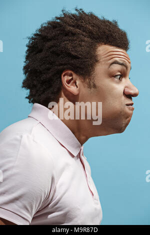 The young emotional angry man screaming on blue studio background Stock Photo