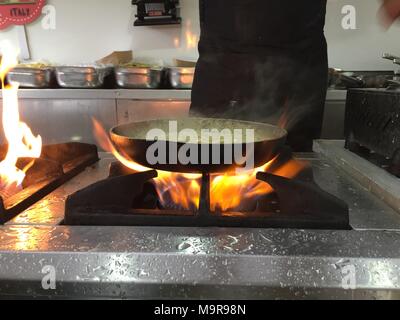 Chef Cooking With Fire In Frying Pan.Professional chef in a commercial kitchen cooking flambe style Stock Photo