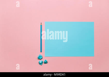 Two tone blue and pink contrast color paper background with crumpled balls and blue wooden pencil. Empty blank for text and design. Stock Photo