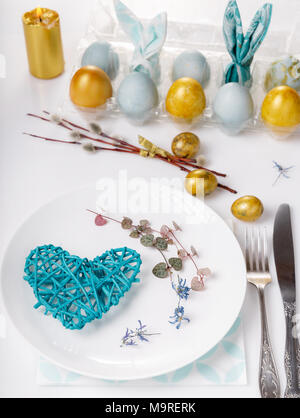 Easter table setting with gold and blue eggs and cutlery. Holidays background. Stock Photo