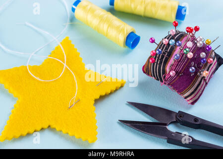 sewing star figures from yellow felt, materials on a light blue background Stock Photo