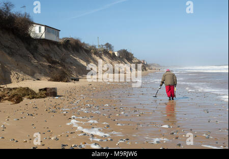 Male  detectorist using metal detector walking along sandy beach Hemsby, Norfolk, England, UK Stock Photo