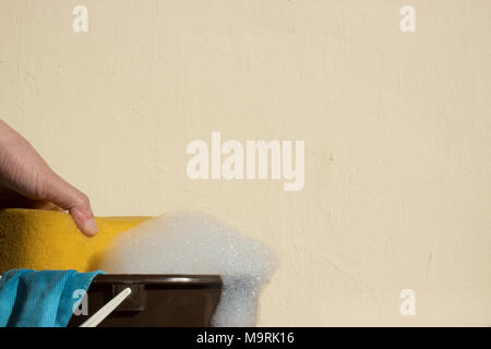 Hand grips sponge which is a foam. Bucket with soap and rags for washing. Stock Photo