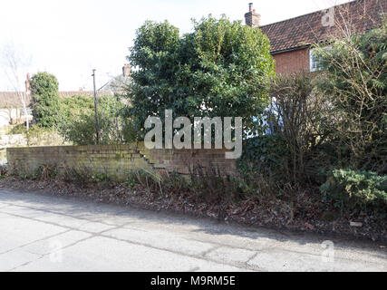 Impact damage to red brick garden wall caused by vehicle reversing, Suffolk, England, UK Stock Photo