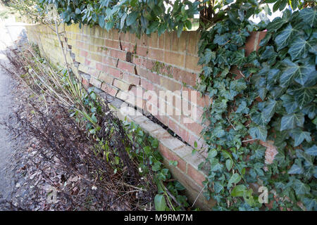 Impact damage to red brick garden wall caused by vehicle reversing, Suffolk, England, UK Stock Photo