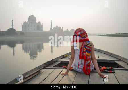 An Asian woman watching sunset over Taj Mahal from a wooden boat. Stock Photo