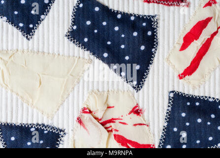 Hand-made textile background with colored pieces of different fabrics sewn on white fabric. Stock Photo
