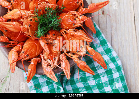 Old bowl with red boiled crawfish on a wooden table in rustic style, close-up, selective focus on some crawfishes Stock Photo