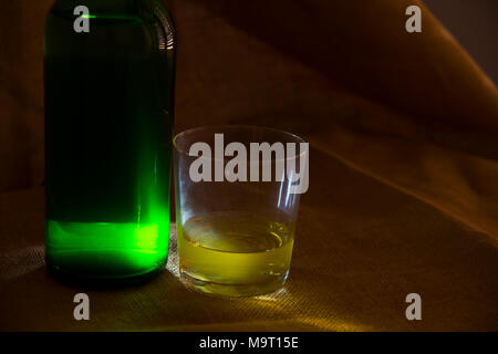 Glass and bottle of cider, low key. Asturias, Spain. Stock Photo