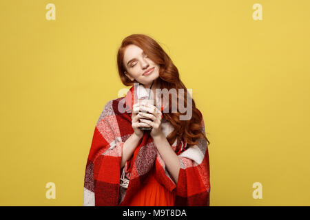 Lifestyle Concept: Portrait of woman basking with plaid and enjoy drinking chocolate Isolated over vivid yellow background Stock Photo